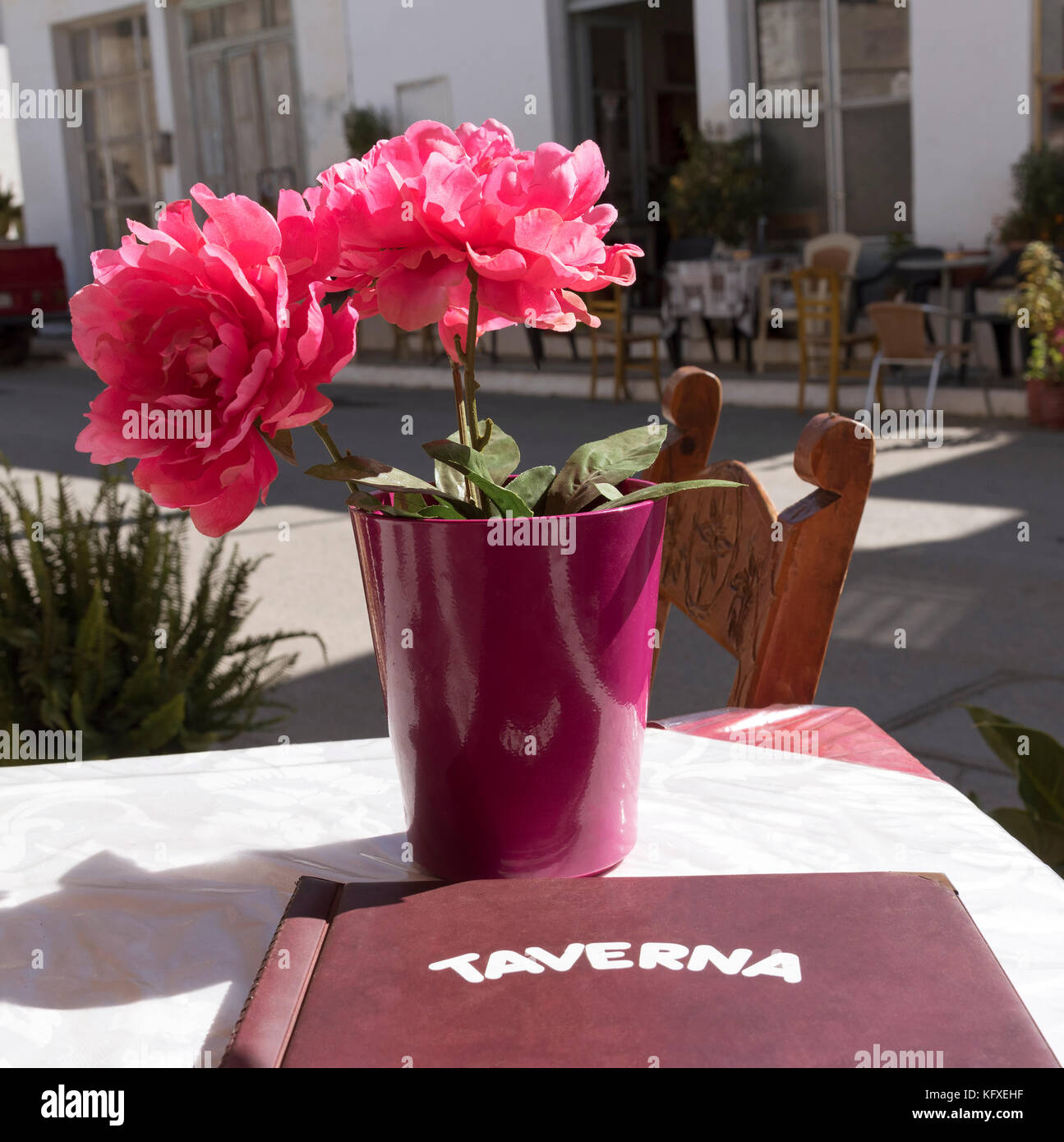 Flores artificiales y un menú en una mesa de taberna. Agios Georgios, meseta de Lasithi, Creta, Grecia. Octubre 2017 Foto de stock