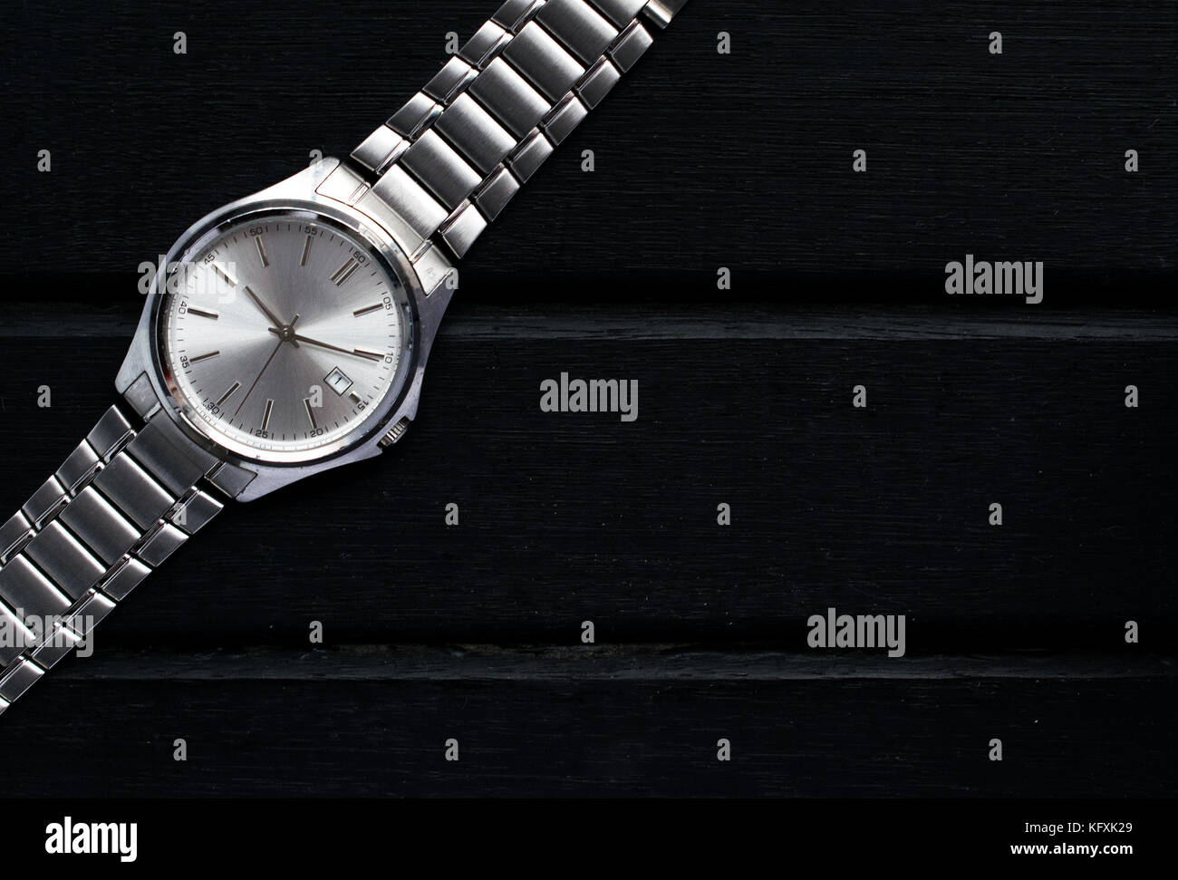 Acero inoxidable plata mens reloj de muñeca sobre una superficie de madera negra, con un montón de espacio y el contraste de la copia Foto de stock