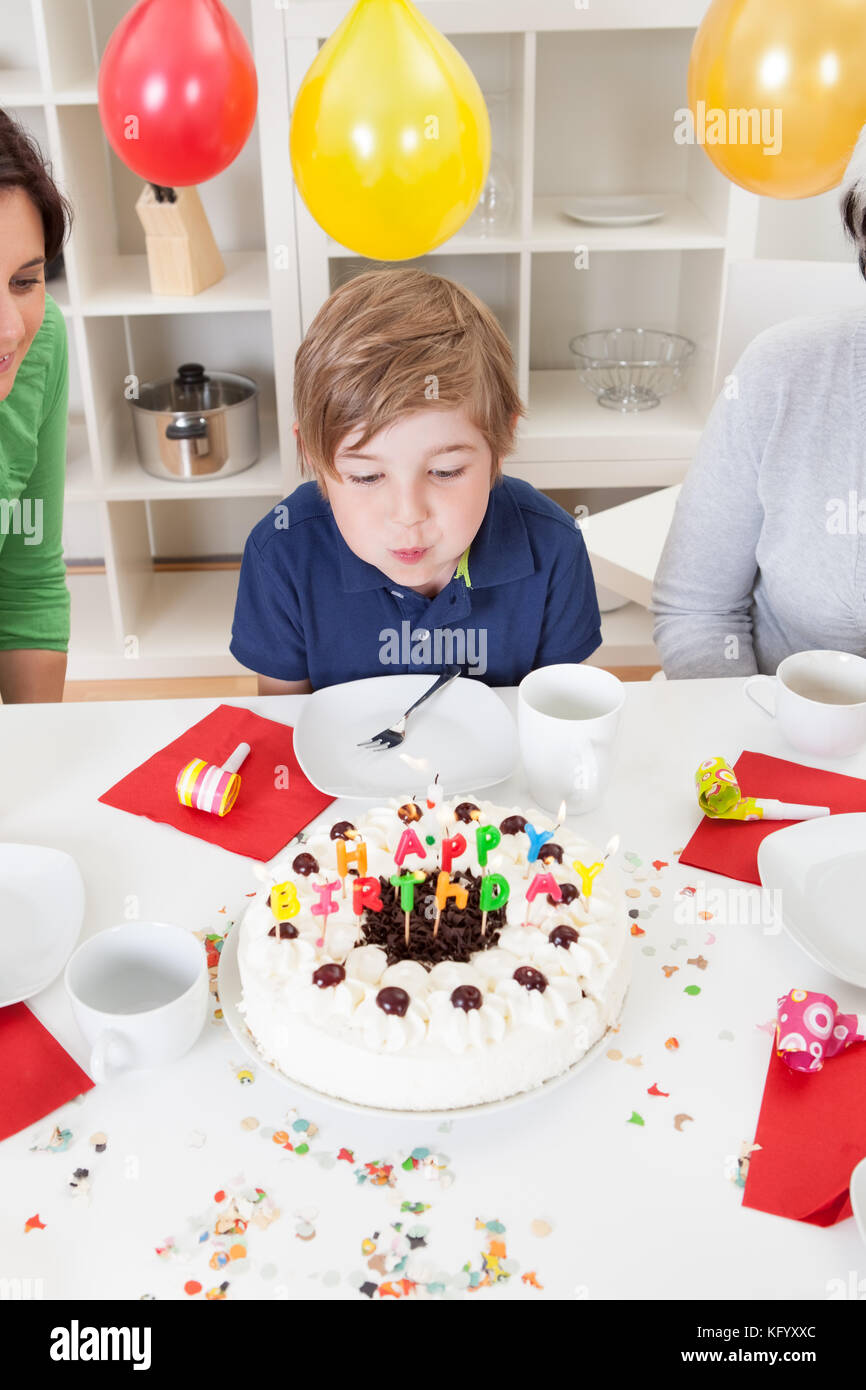 Lindo niño de 3 años está celebrando su cumpleaños y comiendo un delicioso  pastel hermoso, foto de un niño con globos