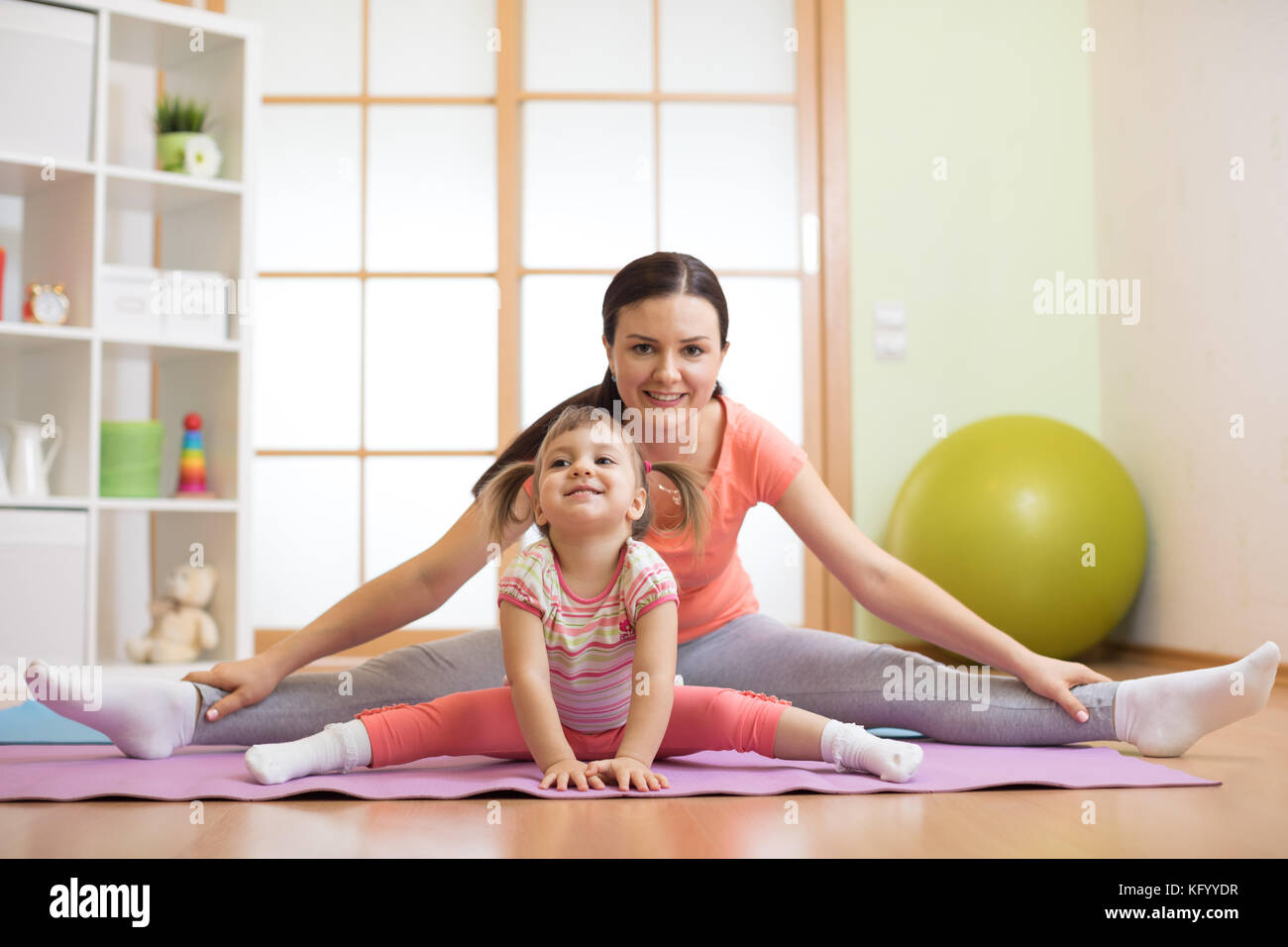 Madre e hija haciendo ejercicios físicos en la alfombrilla en casa Foto de stock