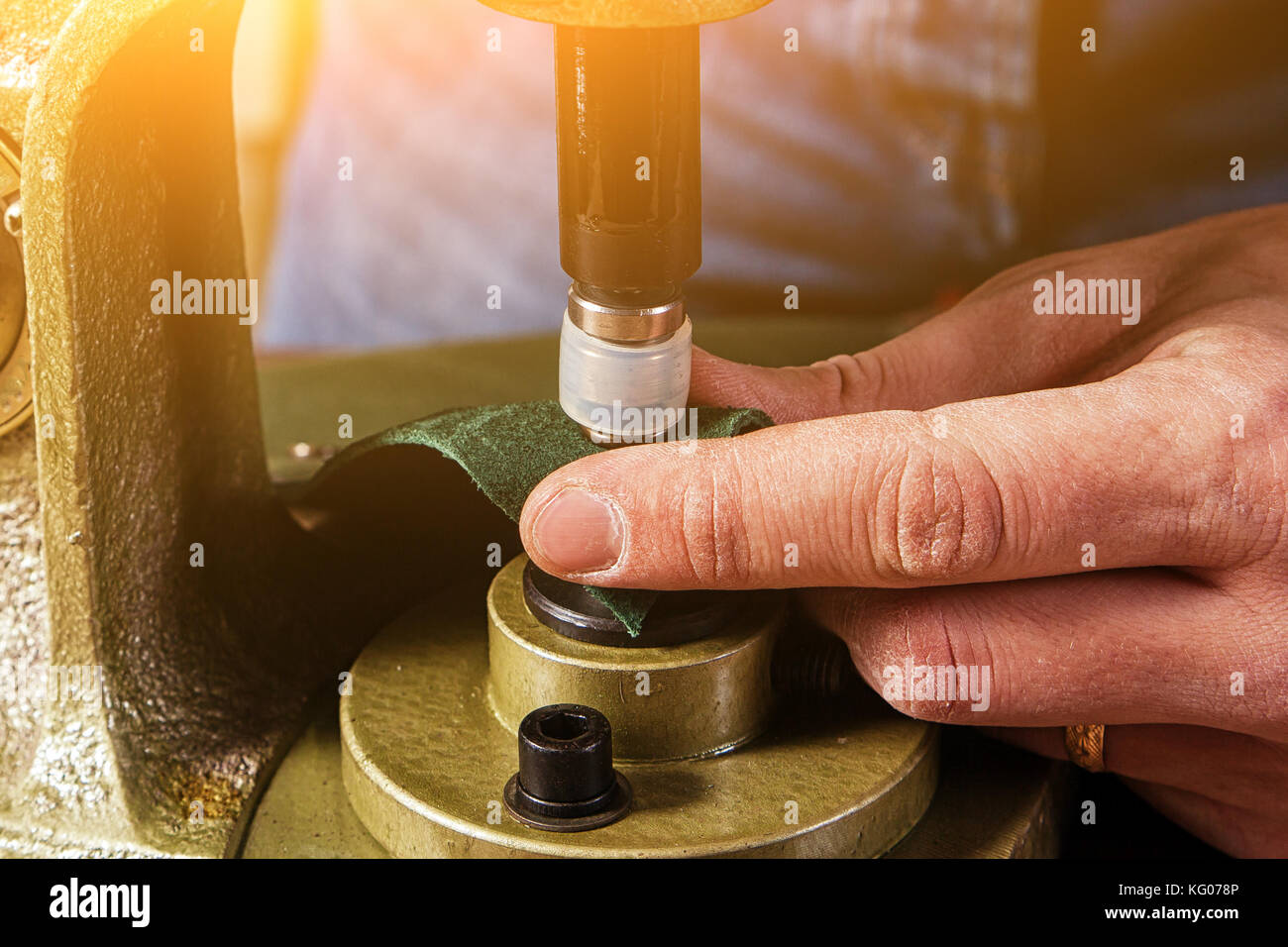 Un primer plano de un peletero colgajos botones black metal en una correa de  cuero marrón en una vieja máquina remachadora de mano Fotografía de stock -  Alamy
