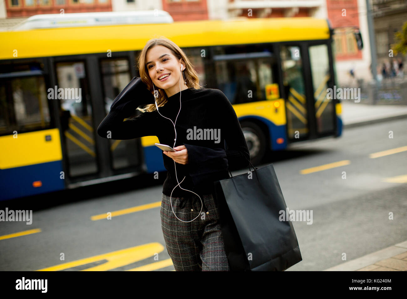 Mujer joven esperando un taxi o autobús en la calle en la ciudad Foto de stock