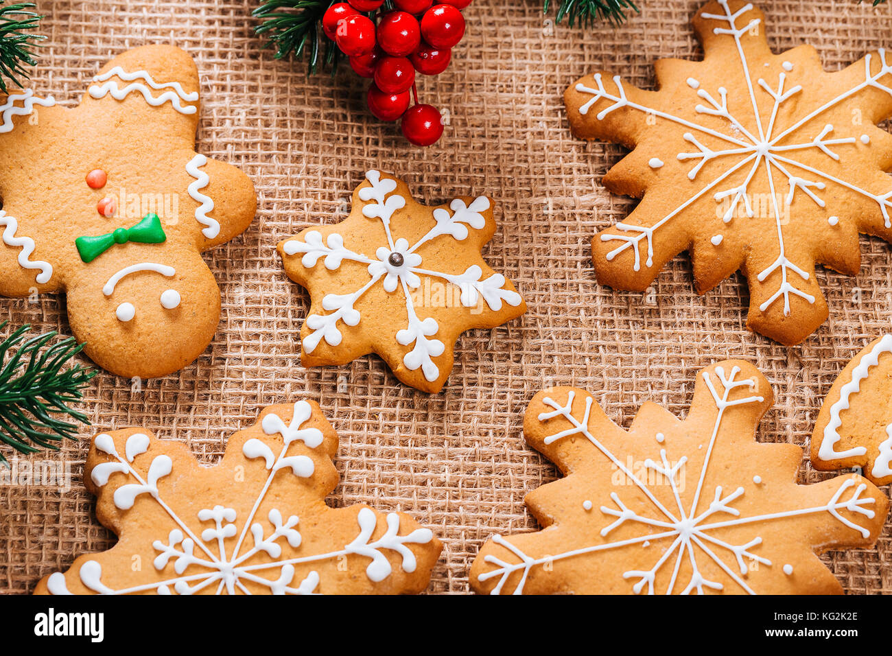 Gingerbread cookies caseros de navidad con ramas de árbol de navidad y año nuevo la decoración en la mesa con el mantel arpillera. feliz navidad tarjeta postal. Foto de stock