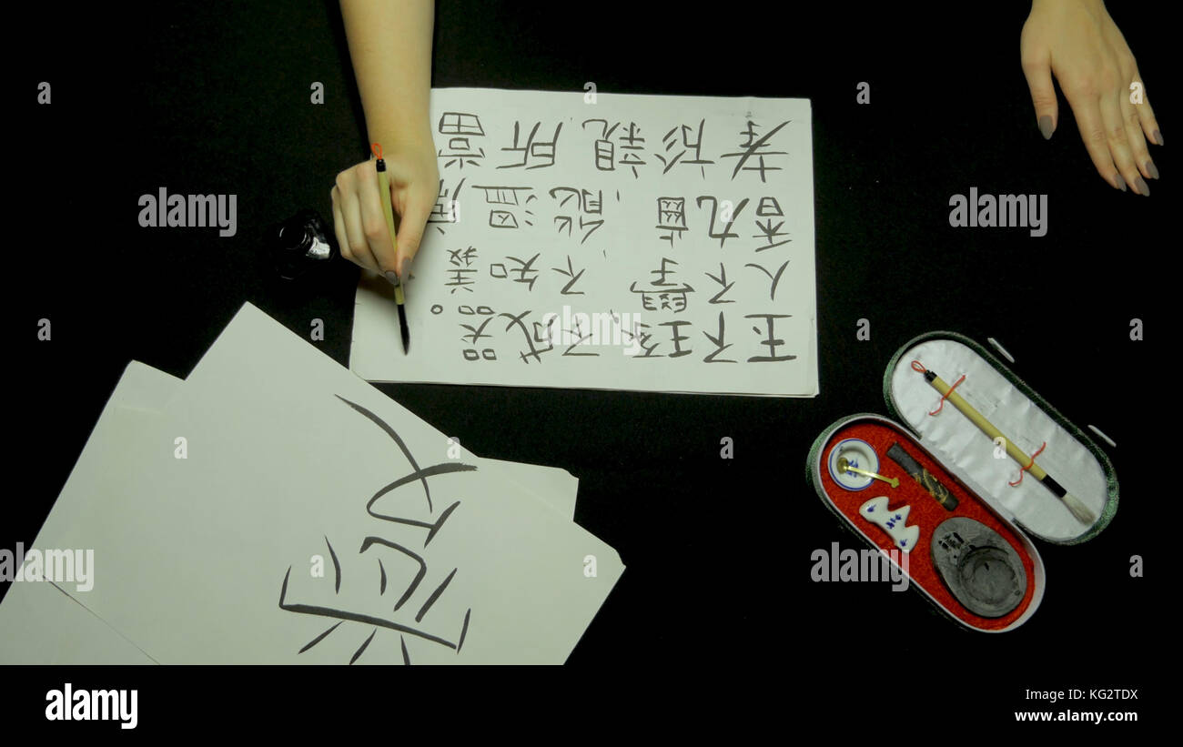 Escritura a mano femenina caligrafía china con pincel y tinta sobre papel  de arroz. cerrar sobre la mano que sujeta el cepillo al escribir la  caligrafía china la caligrafía y pintura Fotografía