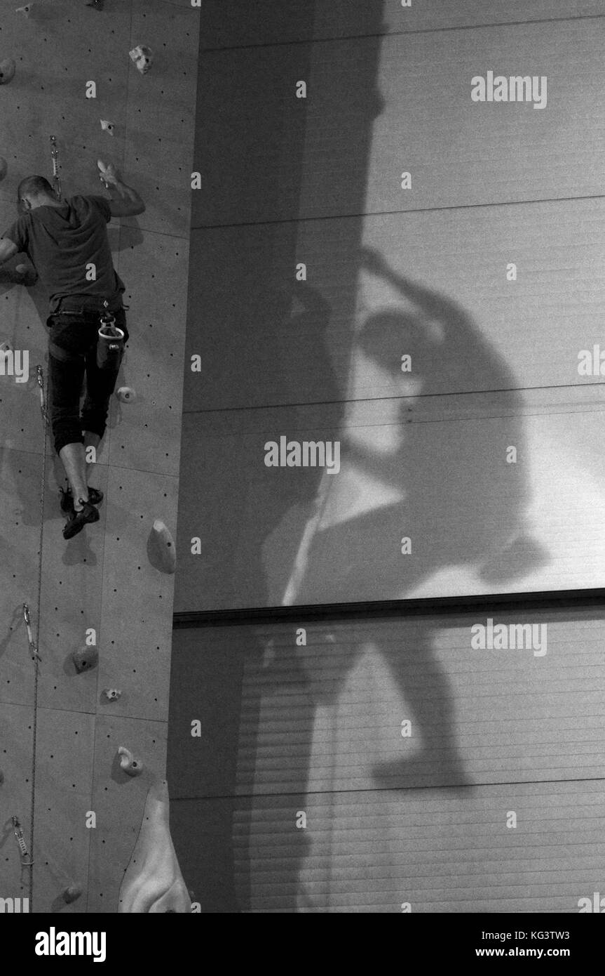 Hombre con cuerdas de escalada en la pared de escalada Foto de stock