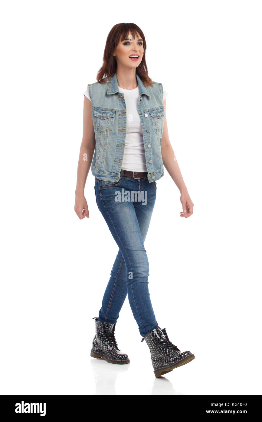 Mujer joven en jeans chaleco y botas negras está caminando y mirando a otro  lado. Vista frontal. longitud completa foto de estudio aislado en blanco  Fotografía de stock - Alamy