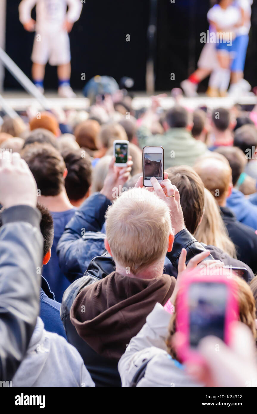 Muchas personas en un concierto al aire libre con el uso de teléfonos móviles para tomar fotografías o vídeos Foto de stock