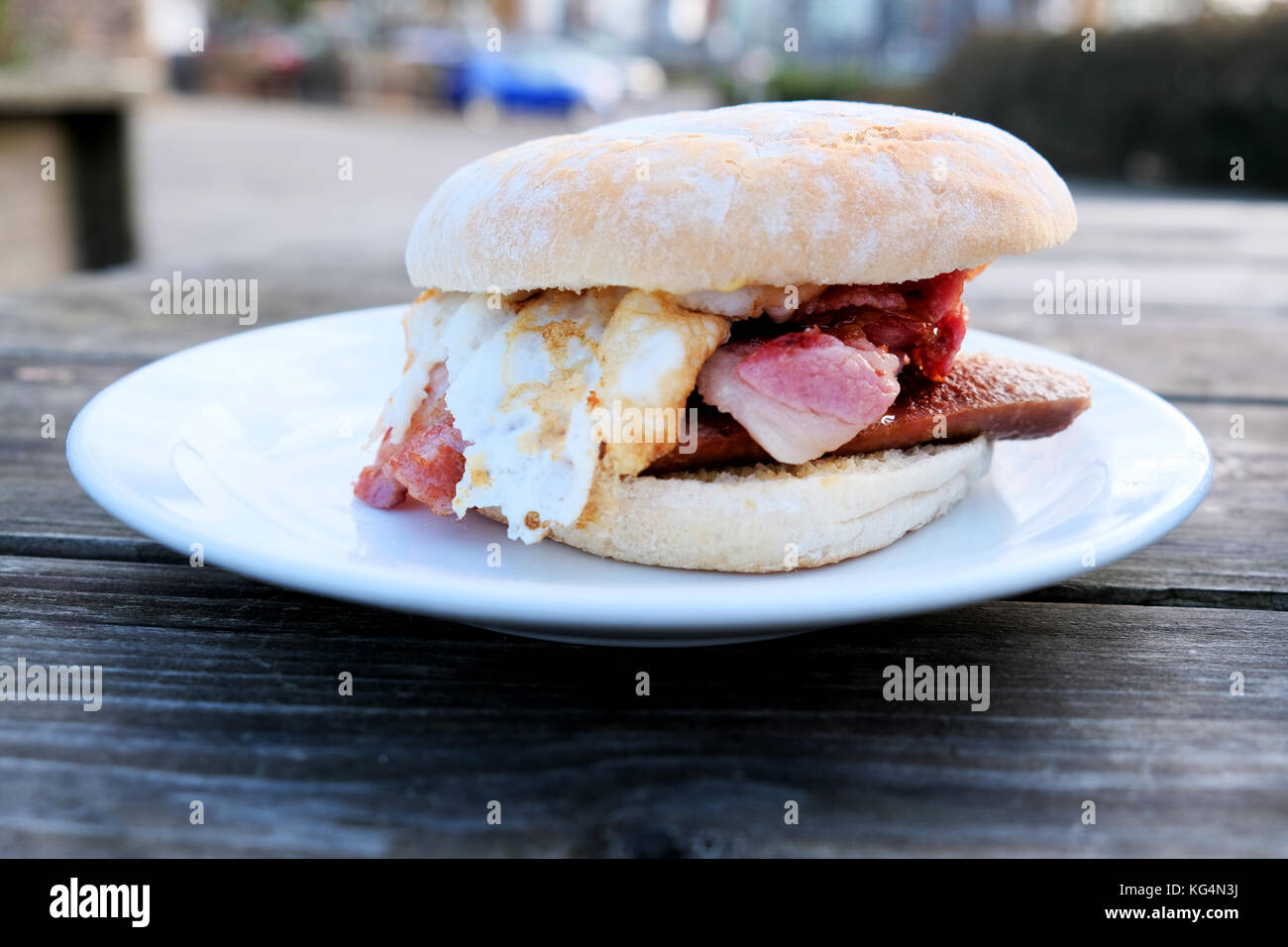 Un sabroso y delicioso desayuno bap compuesto de salchichas, tocino y huevo comprado en una cafetería al aire libre en Bristol, Inglaterra, Reino Unido Foto de stock