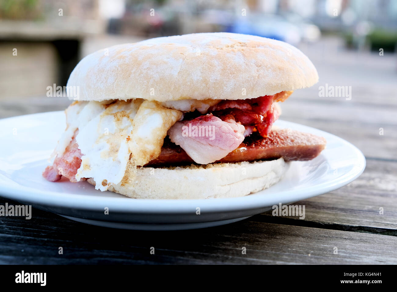 Un sabroso y delicioso desayuno bap compuesto de salchichas, tocino y huevo comprado en una cafetería al aire libre en Bristol, Inglaterra, Reino Unido Foto de stock