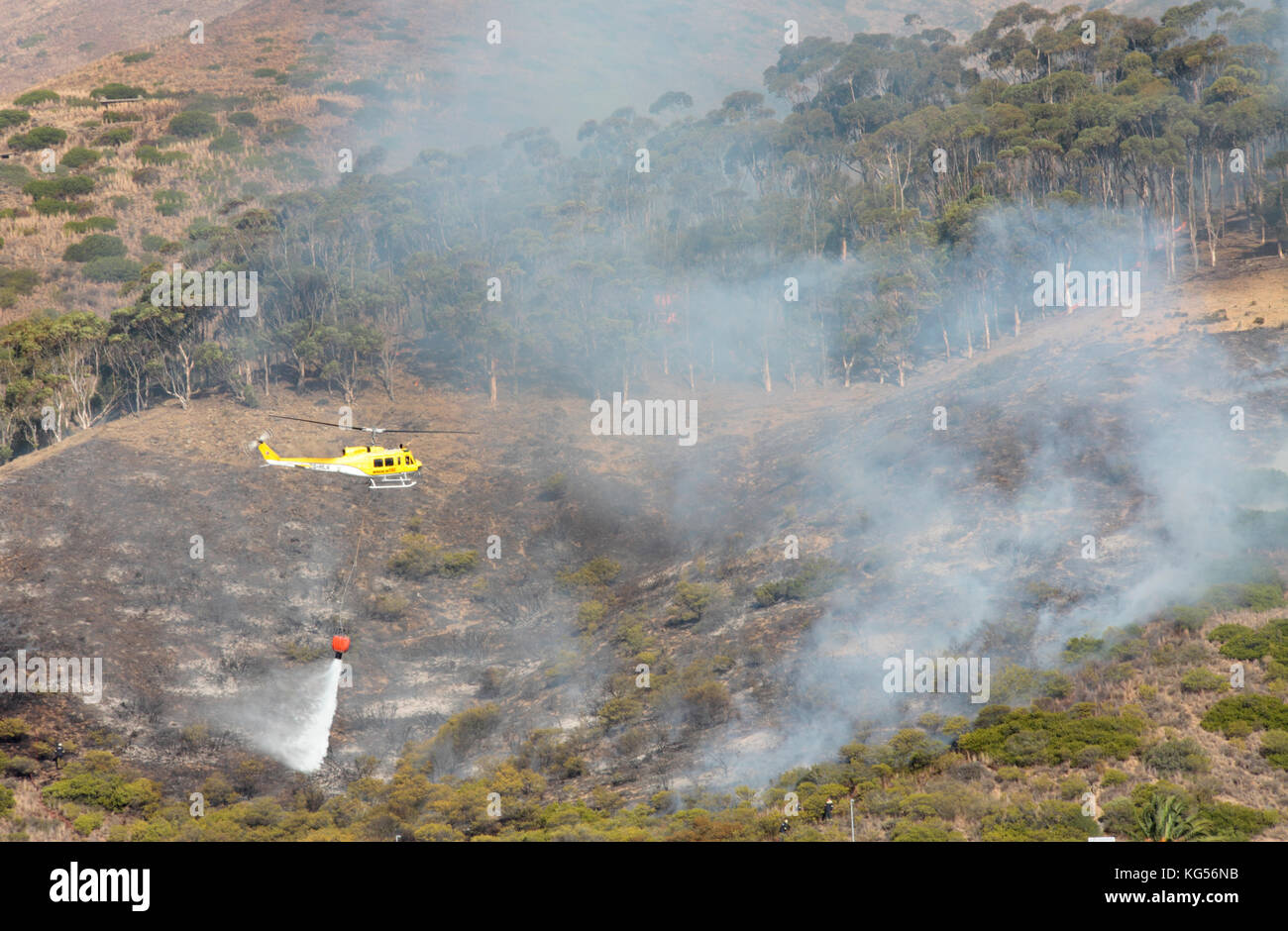 Helicóptero lanzando agua sobre el fuego salvaje, Signal Hill, Ciudad del Cabo, Sudáfrica. Foto de stock