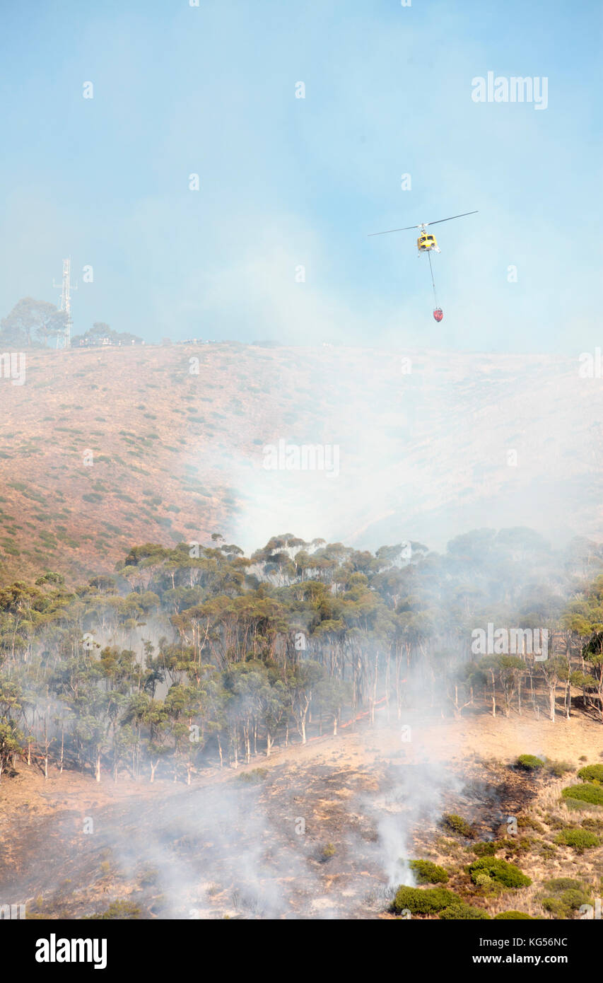 Helicóptero lanzando agua sobre el fuego salvaje, Signal Hill, Ciudad del Cabo, Sudáfrica. Foto de stock