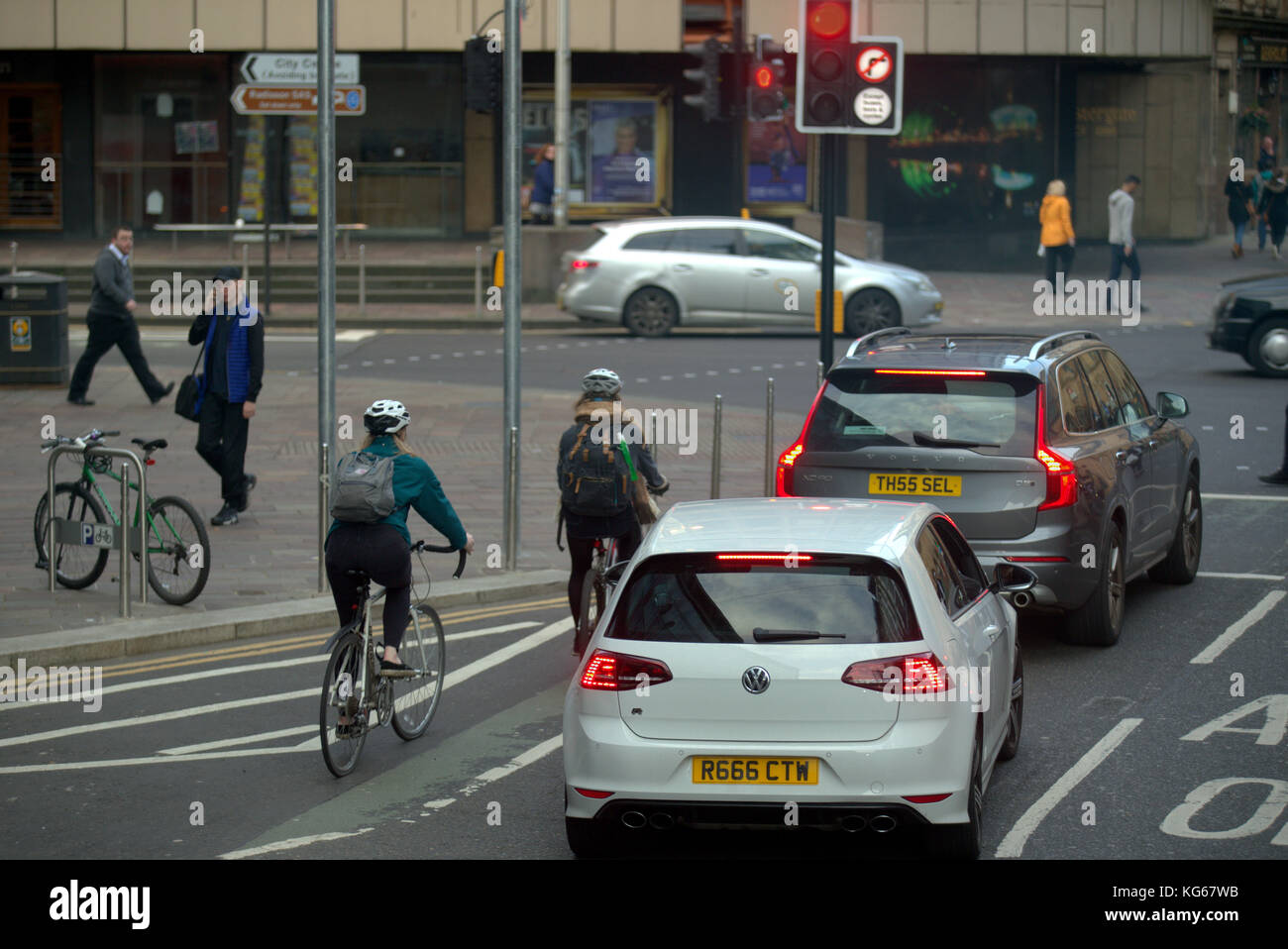 Mujer femenina ciclistas en luces rojas acercarse del tráfico visto desde atrás en Hope Street y Argyle St intersección central station Foto de stock