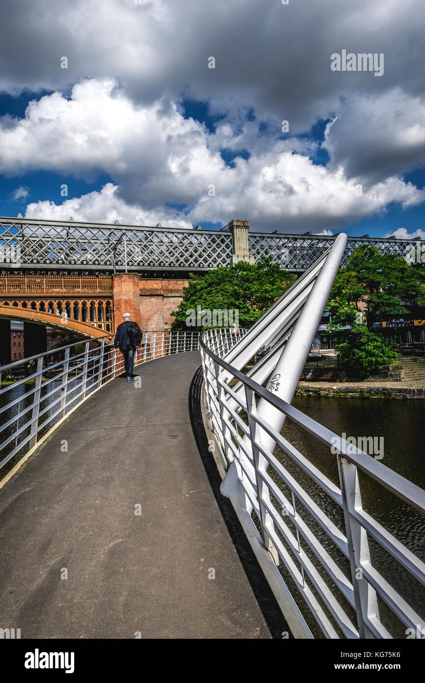 Hombre caminando por un puente sobre el Bridgewater Canal, en el centro de Manchester, Reino Unido Foto de stock