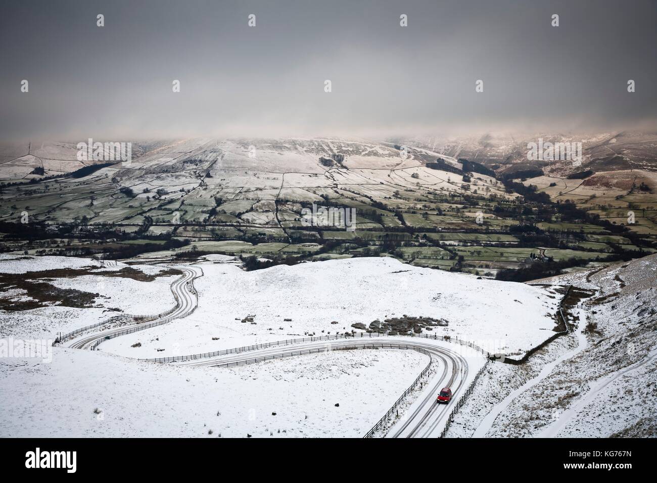 Un coche por una carretera de montaña cubiertas de nieve en invierno. edale valle, Peak District, reino unido Foto de stock