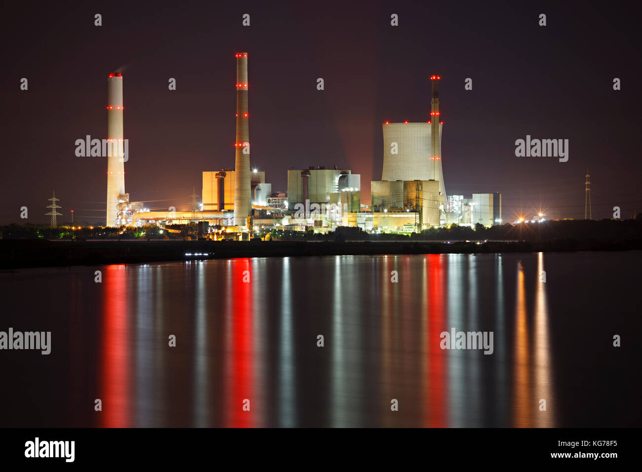 Una planta de energía de carbón en la noche con reflejo en un río. Foto de stock