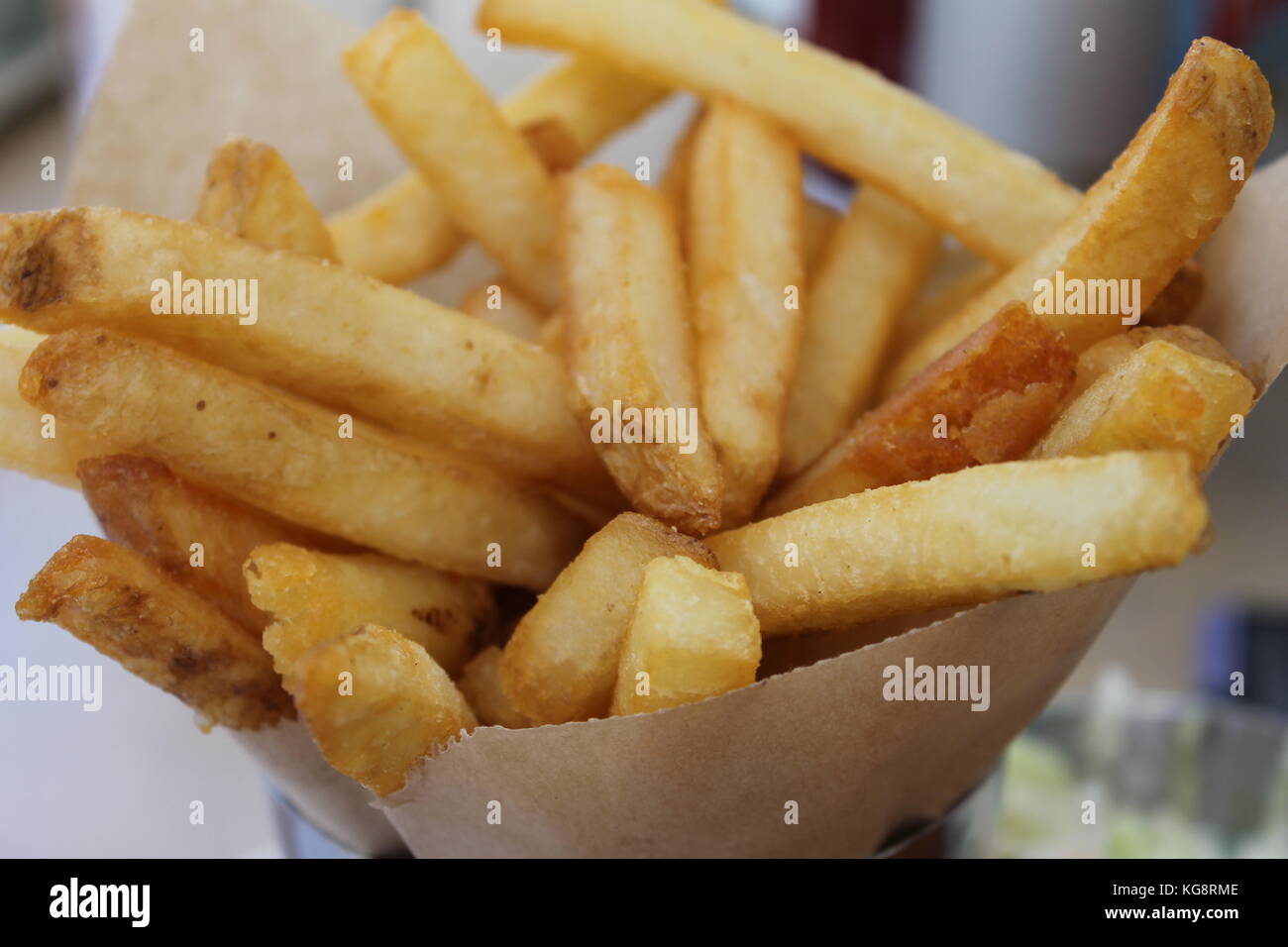 Patatas fritas recién cortadas en un cono de papel marrón Foto de stock