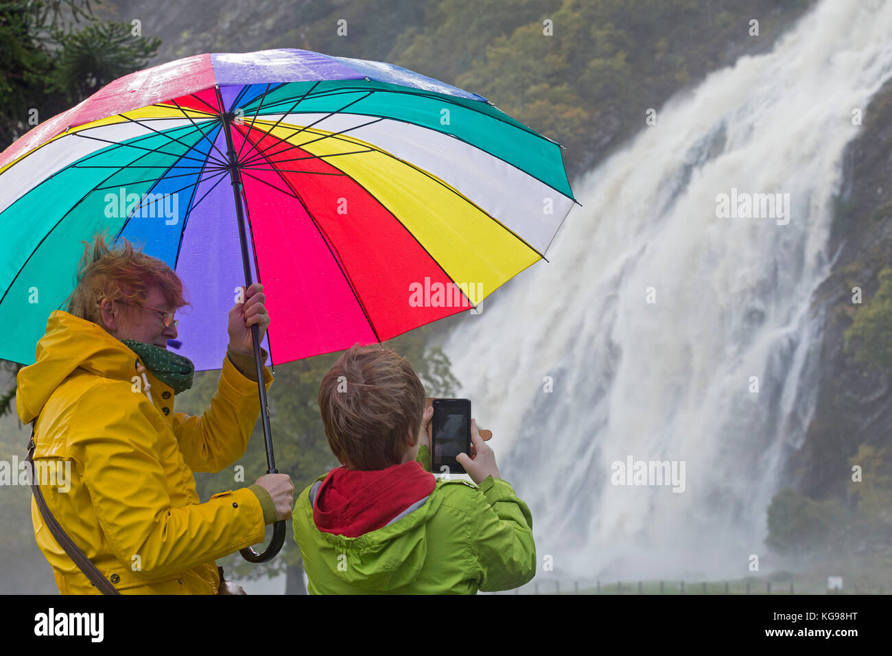 Niño tomando fotos de cascada Powerscourt, madre sosteniendo un paraguas, Enniskerry Wicklow, Irlanda, Co. Foto de stock