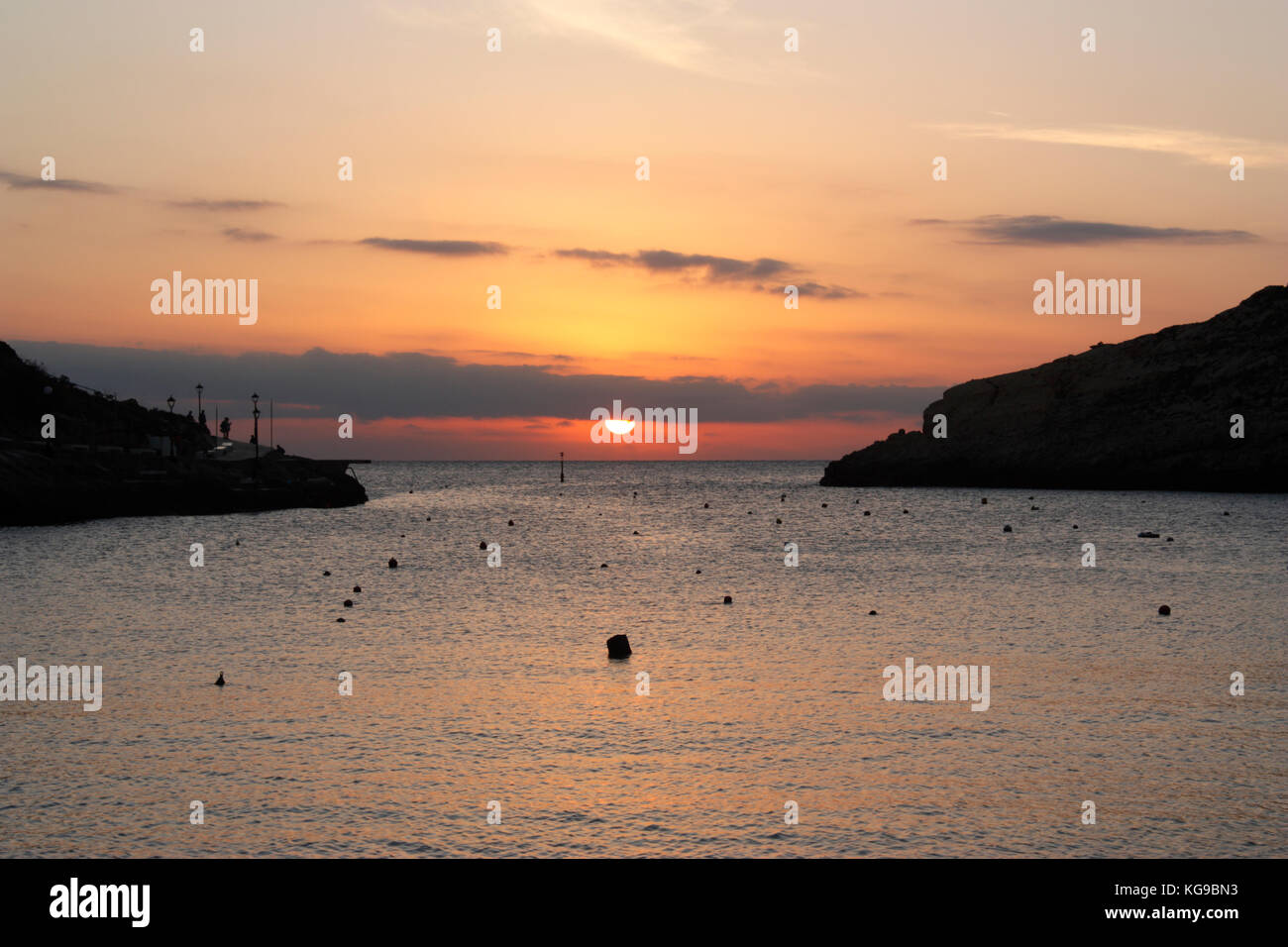 Puesta de sol sobre el Mar Mediterráneo, visto desde la ciudad balnearia de Xlendi, en Gozo, Malta Foto de stock