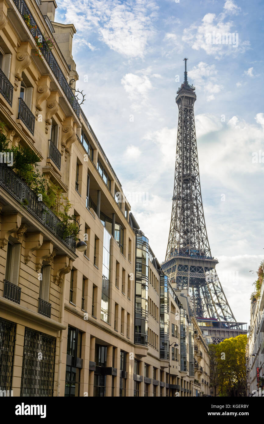Vista desde una calle adyacente a la majestuosa Torre Eiffel en su vecindad inmediata con edificios típicos parisinos en primer plano. Foto de stock