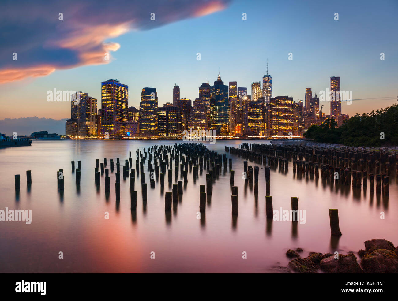 Nueva York Manhattan skyline atardecer tormentoso cielo del rascacielos con Brooklyn Old Pier 1 pilotes de madera de la ciudad de Nueva York el estado de Nueva York, EE.UU. Foto de stock