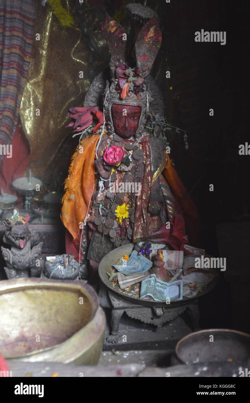 Escultura nepalesa de metal hindú con la cara roja de un dios en un pequeño santuario en Bhaktapur, valle de Katmandú. Foto de stock