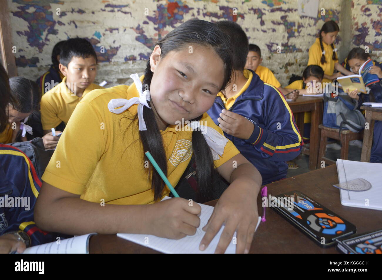 Adolescente nepalés con arcos blancos dibujando el pelo y posando para la foto, en el fondo otros estudiantes, Katmandú, Nepal. Foto de stock