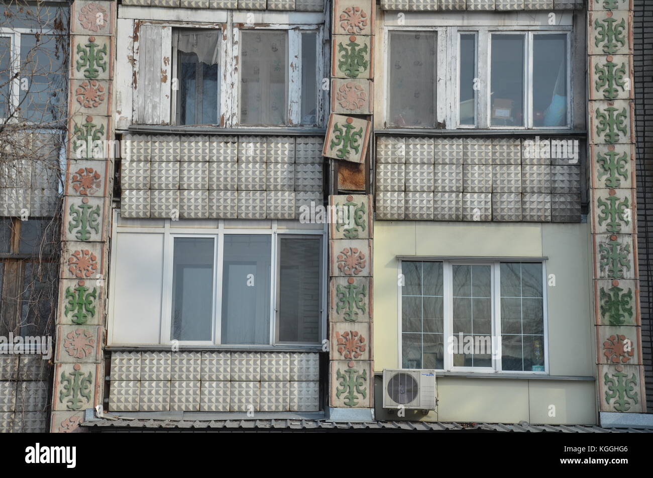 Las baldosas antiguas decoradas se desprenden de la fachada de un antiguo edificio soviético de apartamentos en Kakakhstan. declinar. creación rápida. caída aparte, todavía en uso, fachada Foto de stock