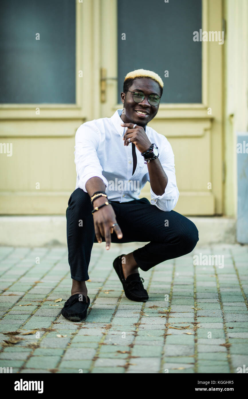 cartel seriamente Cenar Apuesto hombre afro americana vistiendo ropa casual en la ciudad moderna se  encuentra cerca del edificio Fotografía de stock - Alamy