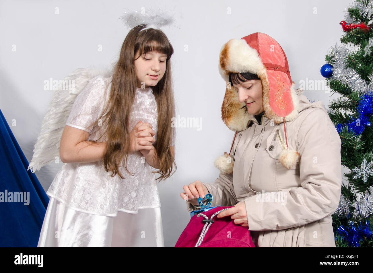 Mujer en ropa de invierno le da un regalo a una chica en un traje de angel  Fotografía de stock - Alamy