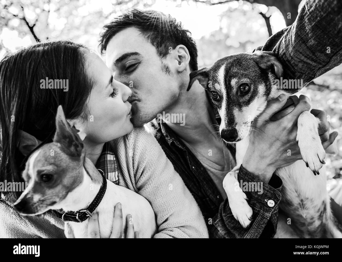Feliz pareja joven con dos bonitos perros haciendo selfie mientras que  besar en otoño park Fotografía de stock - Alamy
