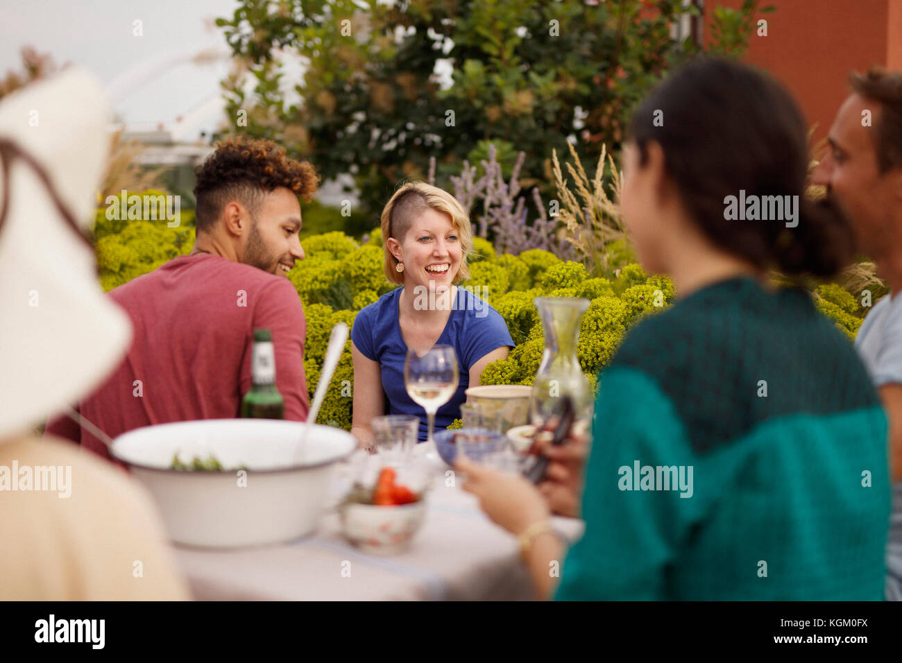 Macho y hembra feliz amigos sentado en la mesa al aire libre en el patio Foto de stock