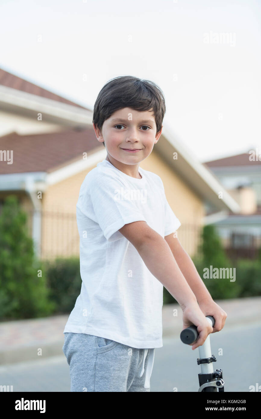 Retrato de niño con empuje scooter en la ciudad Foto de stock