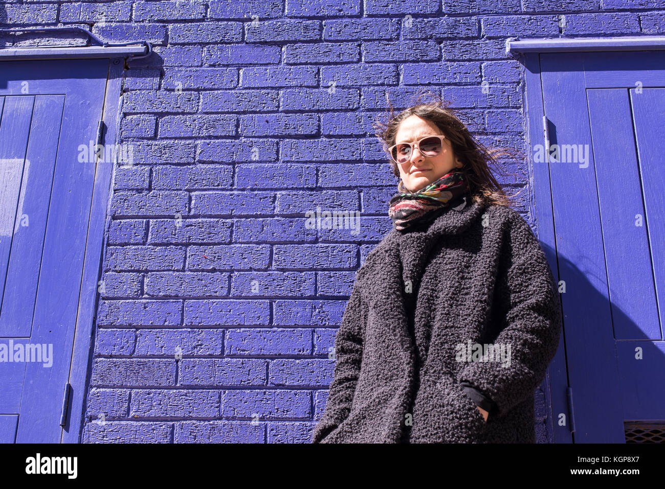 Hermosa mujer en chaqueta con estilo militar cerca de la pared de ladrillo