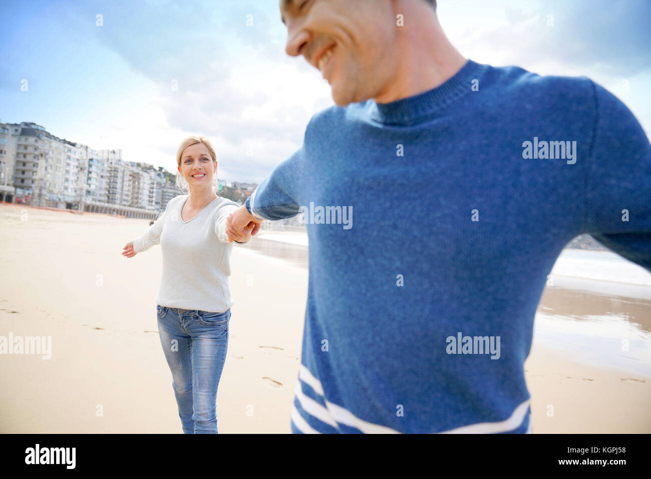 Pareja de mediana edad en la playa divirtiéndose revirtiendo Foto de stock