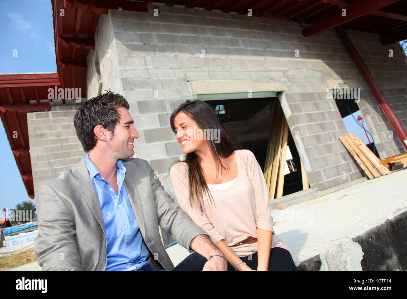 Feliz pareja sentada delante de la casa en construcción Fotografía de stock - Alamy Feliz pareja sentada delante de la casa en construcción Fotografía de stock - Alamy