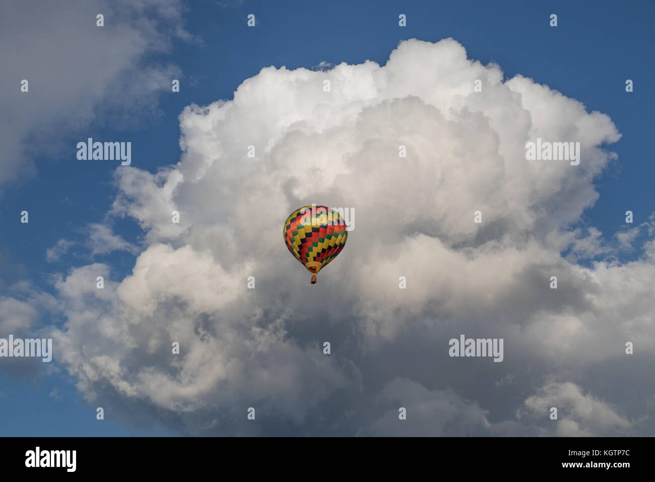 Colorido globo de aire caliente con nubes hinchadas en segundo plano. Foto de stock