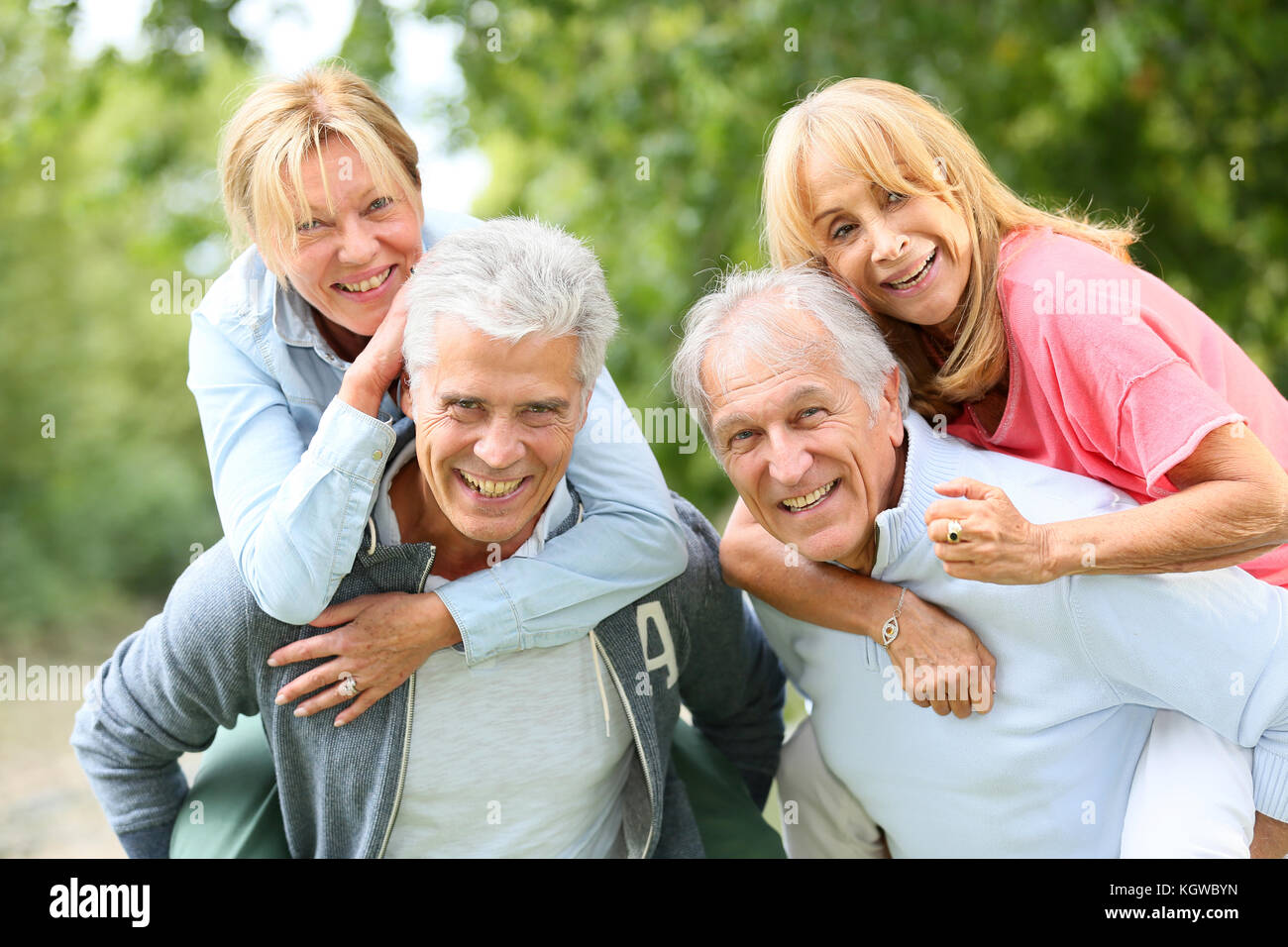 Los hombres mayores dando piggyback ride para las mujeres ancianas Foto de stock