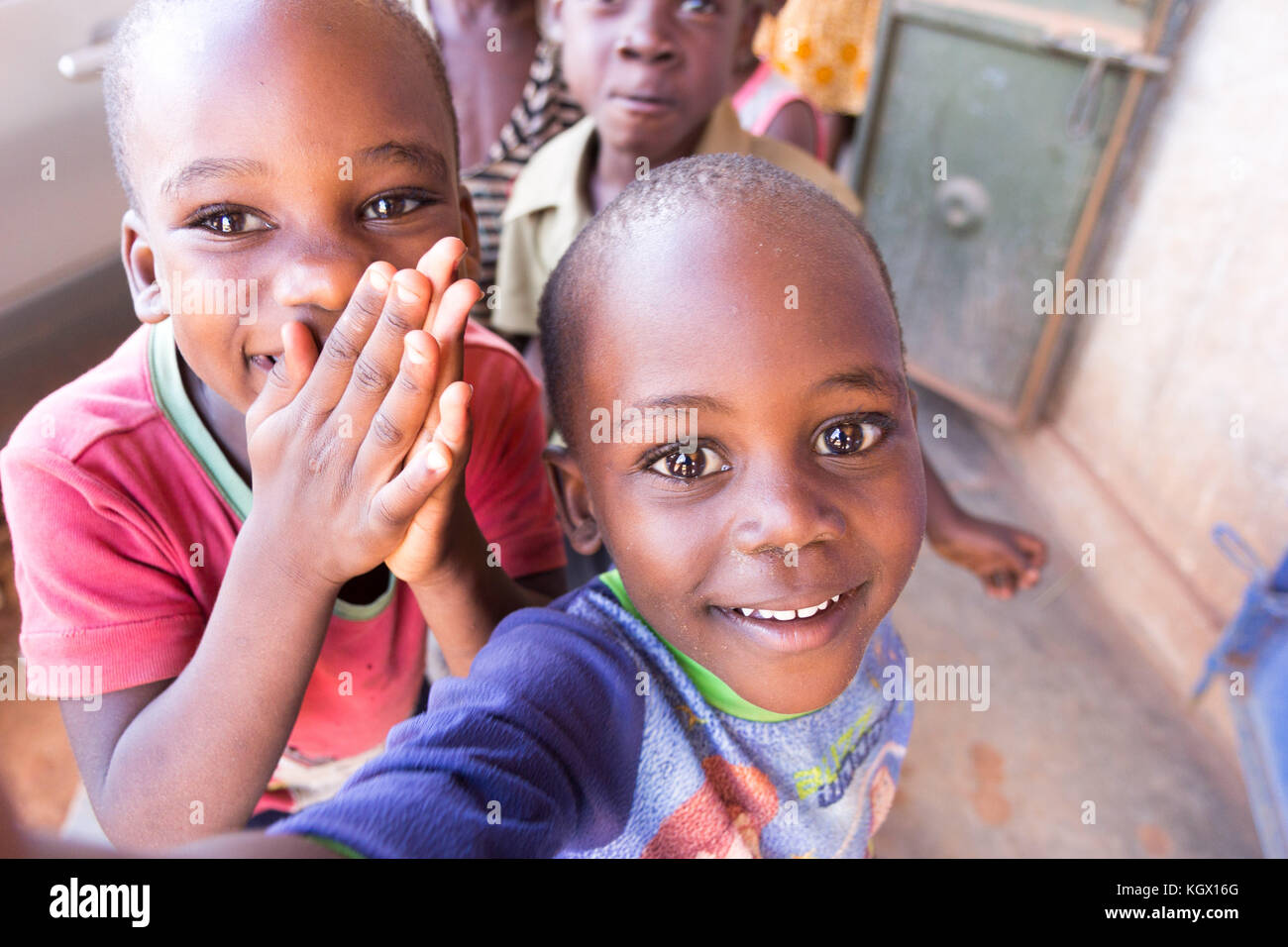 Un montón de niños ugandeses al azar en la calle riendo, sonriendo, saludando y divirtiéndose en el frontal de la cámara. Foto de stock
