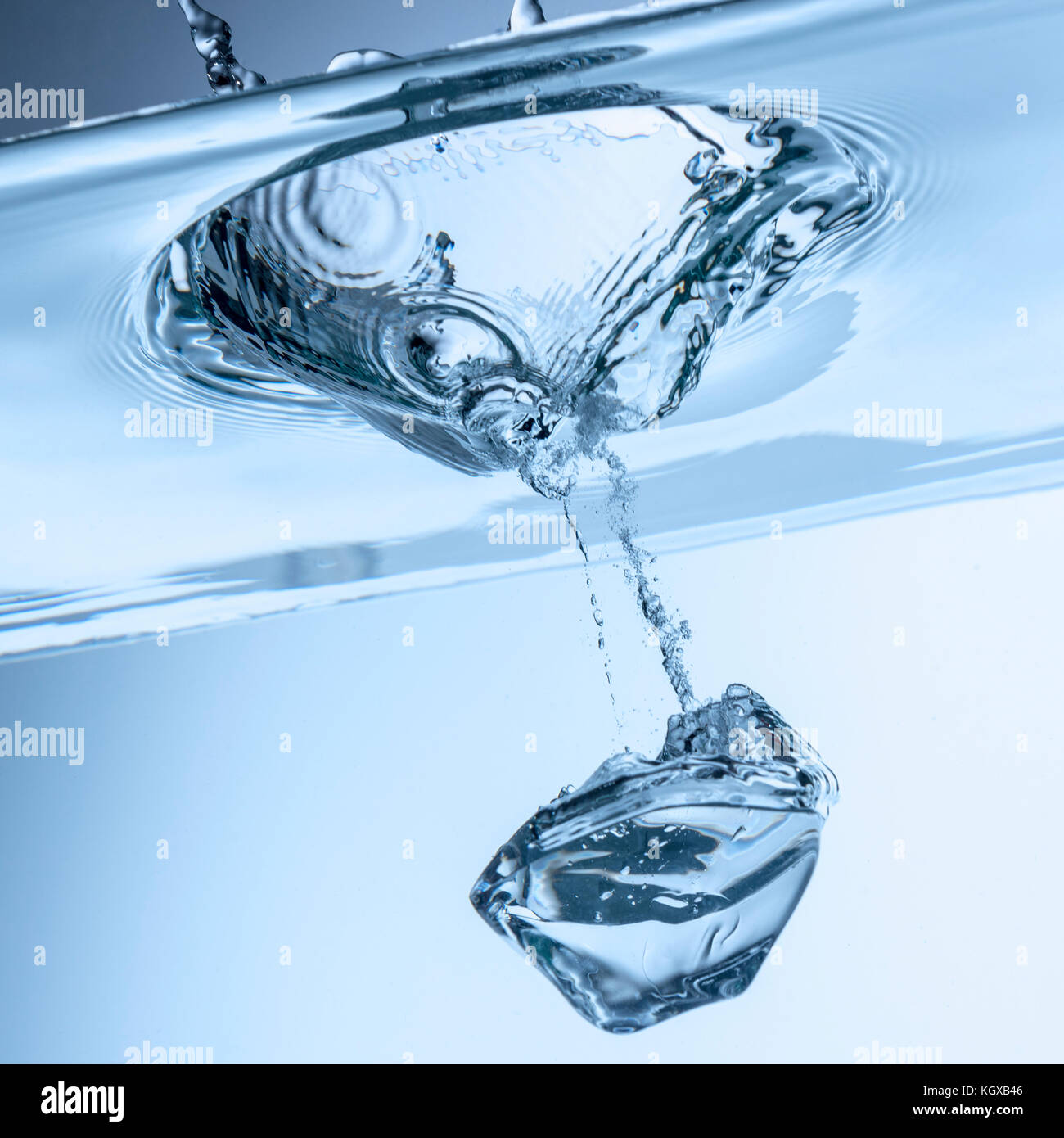 Splash. Cubo de hielo que cae en un tazón de agua limpia, clara Foto de stock