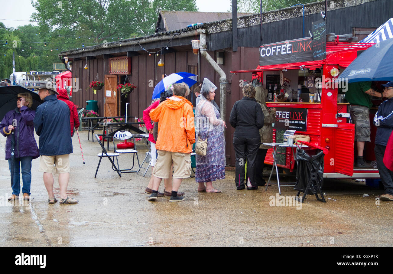 Los asistentes del festival hacen cola en la lluvia para ir al café Foto de stock