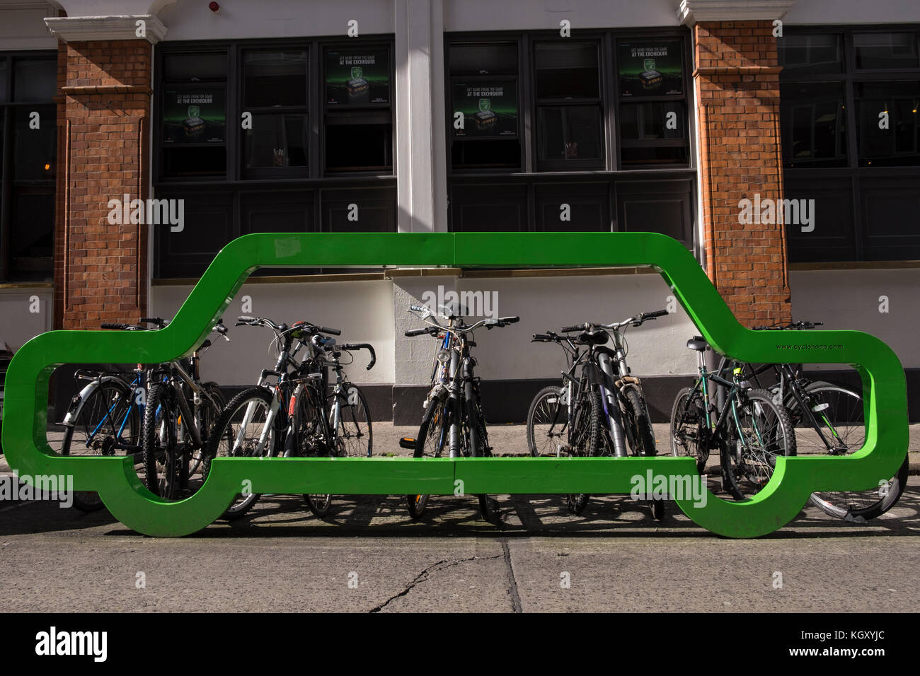 Coche verde del bastidor de metal en forma de espacio de estacionamiento de bicicletas en una calle en el centro de la ciudad de Dublin, cyclehoop, mostrando el número de ciclos de una plaza o Foto de stock