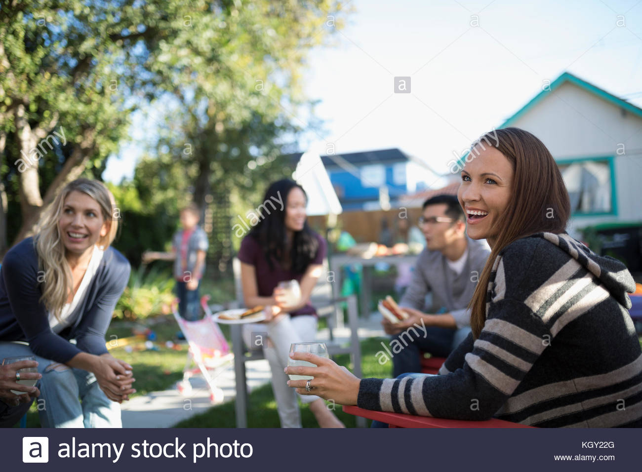 Mujer sonriente disfrutando de jardín barbacoa con amigos vecino Foto de stock