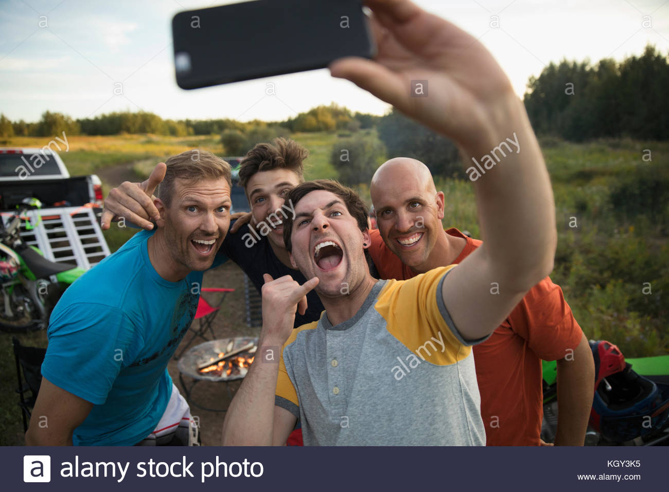 Entusiastas amigos masculinos con cámara de teléfono tomando selfie Foto de stock