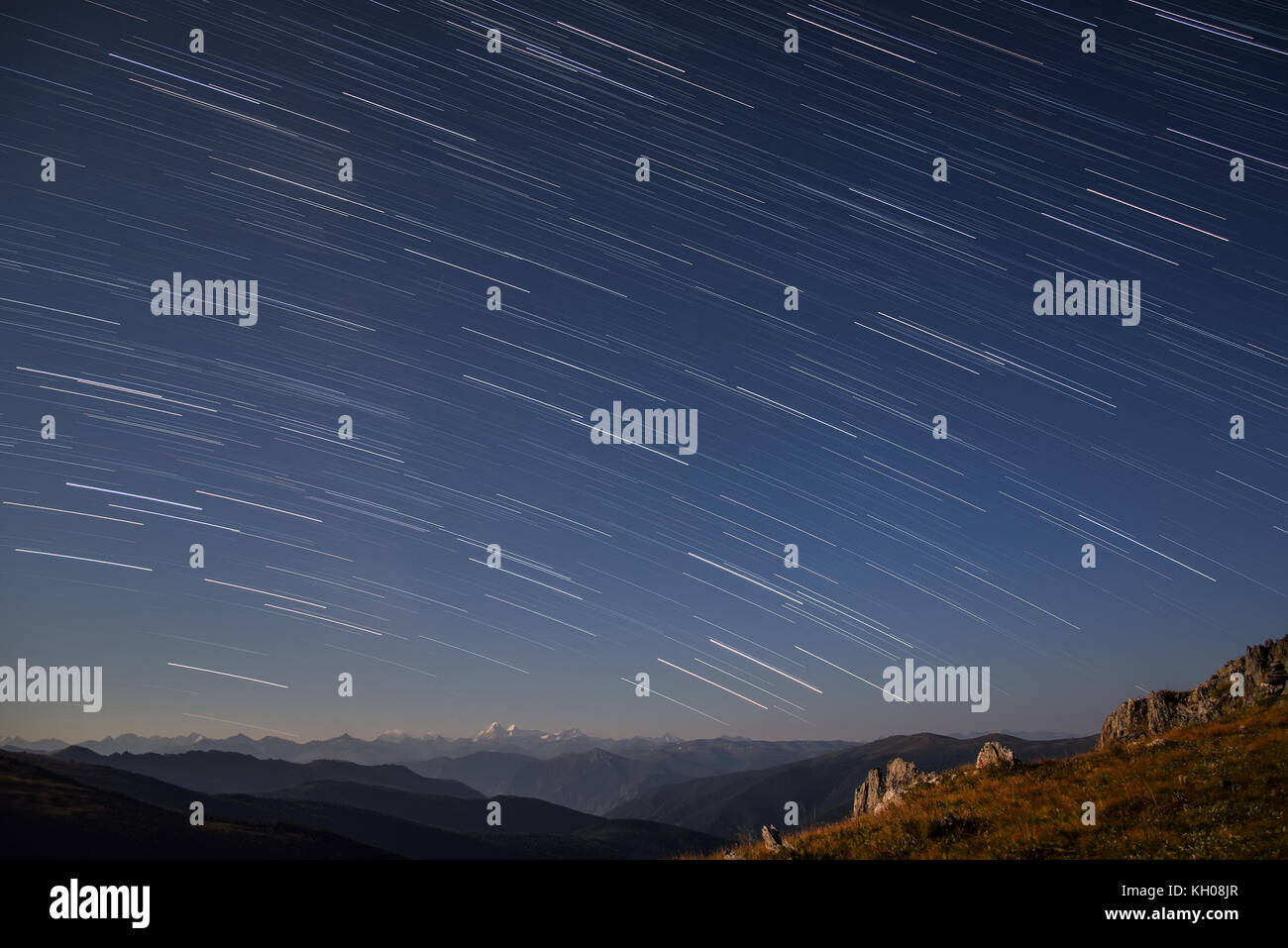 Hermoso paisaje nocturno con trazas de estrellas en el cielo nocturno con un telón de fondo de montañas, rodada en las altas montañas con un tiempo de exposición Foto de stock