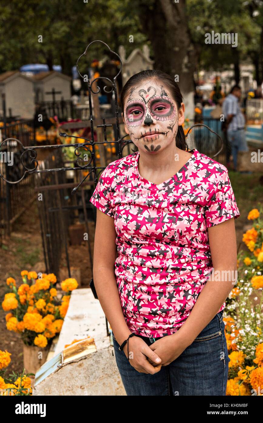 Una niña muestra su pintura de cara Catrina mientras ayuda a decorar una  tumba de un miembro de la familia para el festival del día de los muertos  31 de octubre de