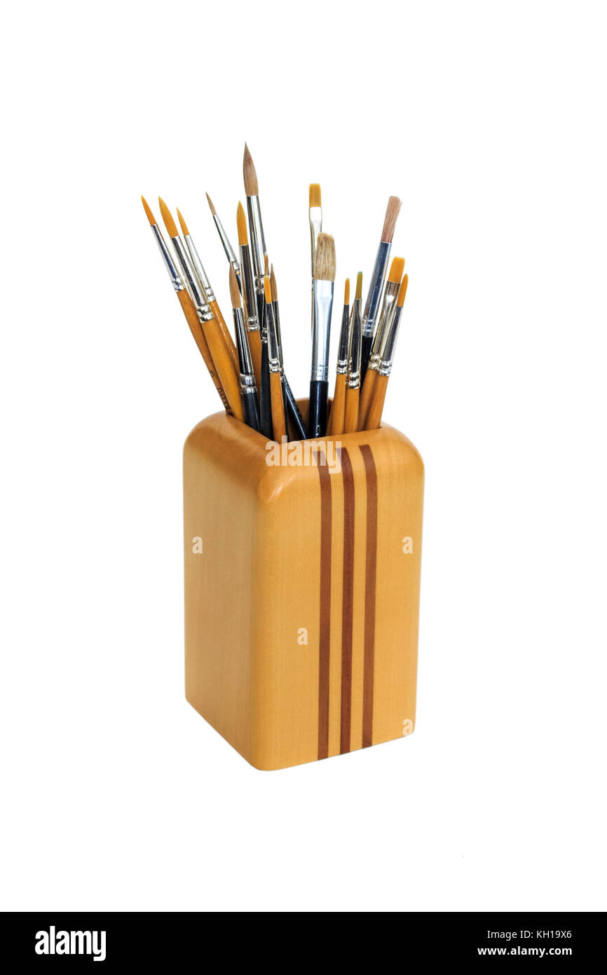 Los pinceles del artista en un contenedor de madera sobre un fondo blanco. Foto de stock