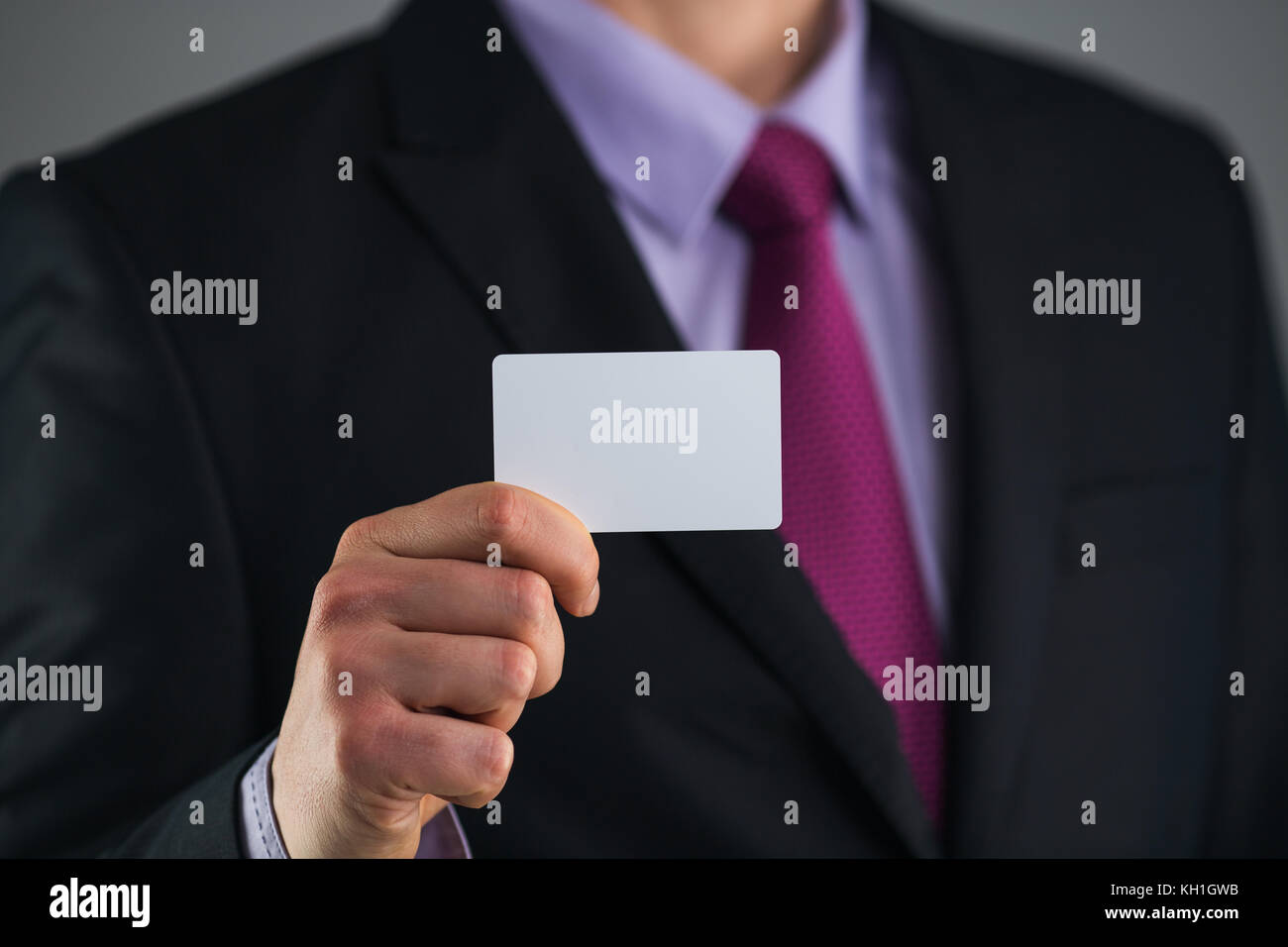 El empresario en un elegante traje y con una corbata, muestra tarjeta con copia espacio, Foto de estudio Foto de stock