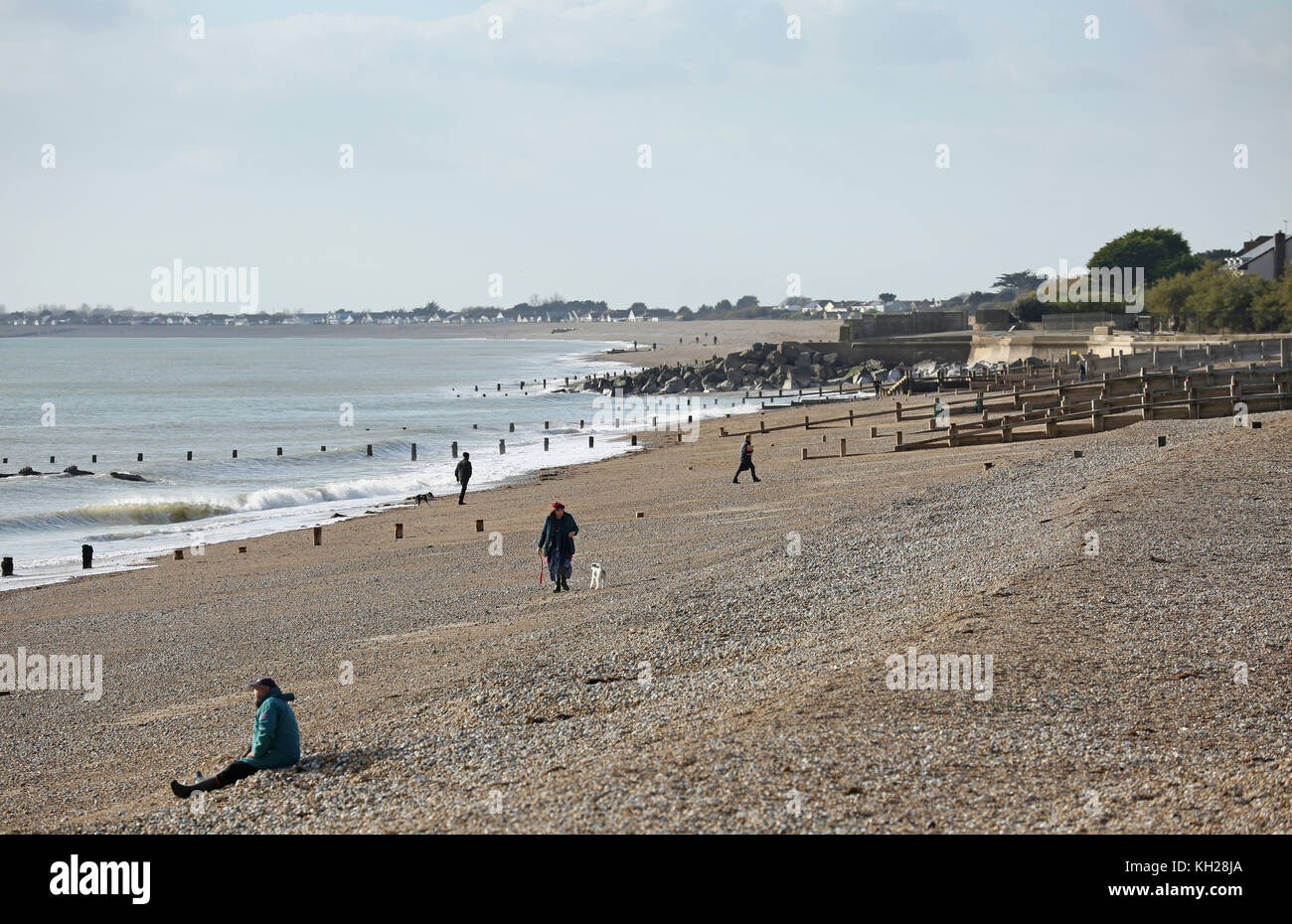 Los visitantes y residentes caminan por la playa Bognor, West Sussex, Reino Unido, en un soleado día de invierno. Incluye andadores de perros, corredores y pescadores. Foto de stock