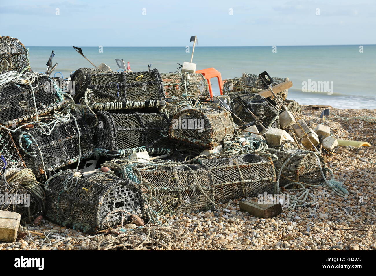 Las ollas de langosta de los pescadores se apilaron en la playa de guijarros en Bognor Regis, West Sussex, Reino Unido. Soleado, día de invierno. Mar tranquilo, marea baja. Foto de stock