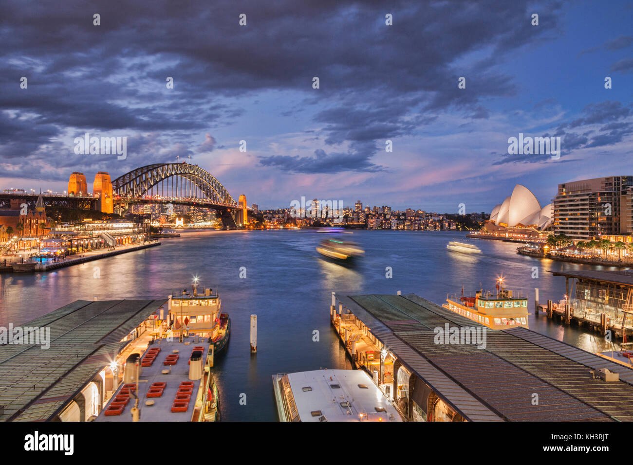 Concurrido puerto de Sydney, iluminado en la penumbra, algunos barcos con desenfoque de movimiento. Foto de stock
